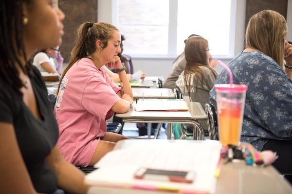 Students in class sitting at desks with notebooks open.